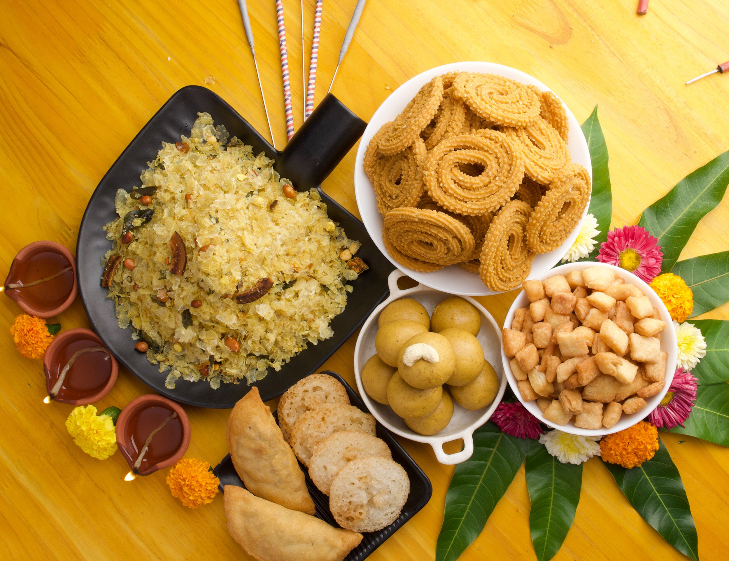 Traditional Diwali faral platter with poha chivda, chakli, laddoo, shankarpali, gujiya, and festive diyas on decorated table